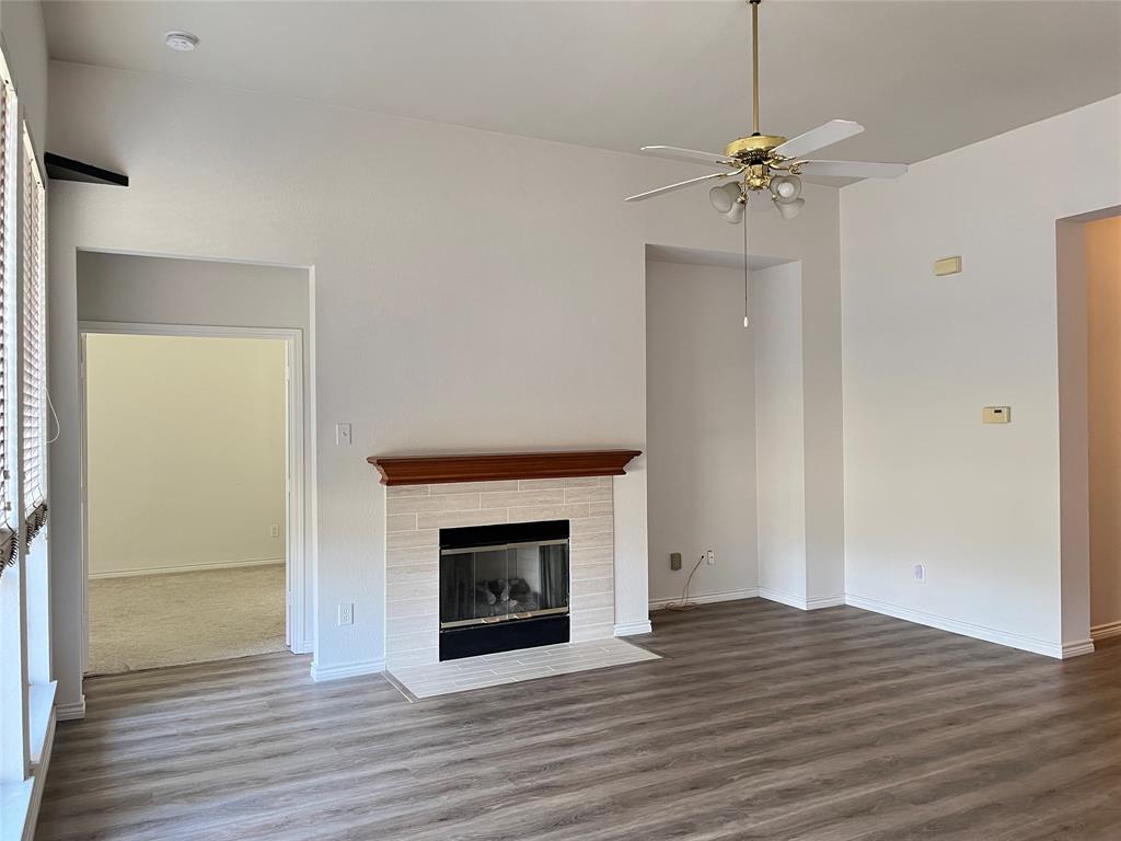 9814 Glenshee Drive Rowlett, TX 75089 - Photo 6 of 25 Unfurnished living room featuring wood finished floors, a fireplace with flush hearth, and ceiling fan