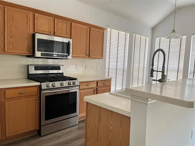 a kitchen with stainless steel appliances a stove microwave and sink