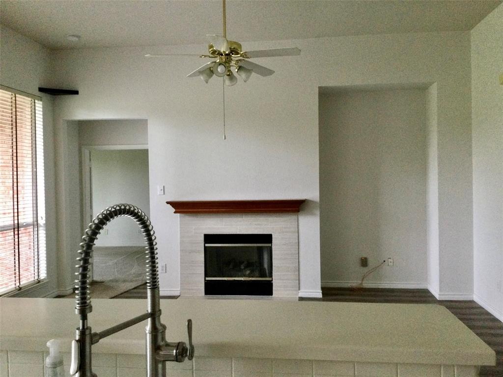 9814 Glenshee Drive Rowlett, TX 75089 - Photo 10 of 25 Unfurnished living room with a fireplace, wood finished floors, and ceiling fan
