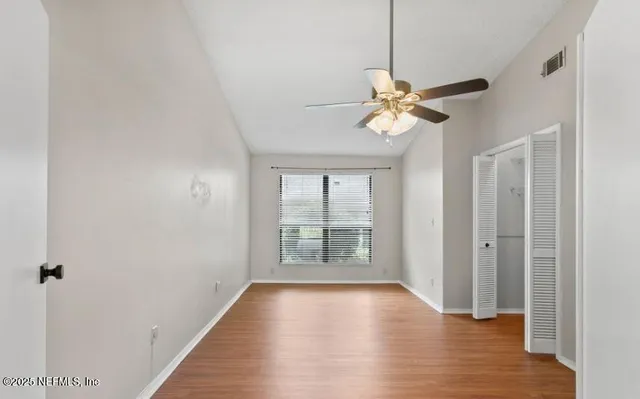 a view of a room with wooden floor chandelier fan and closet
