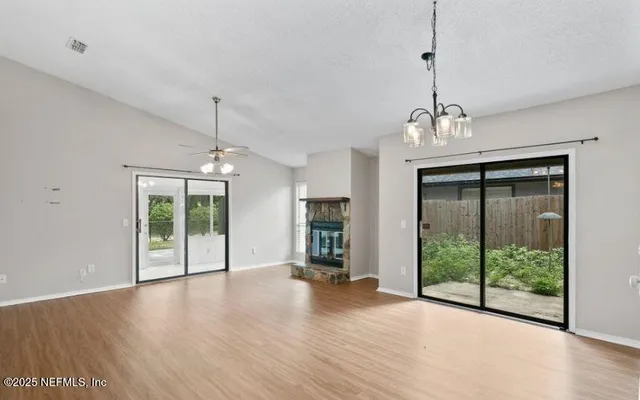 a view of a room with wooden floor fireplace and windows