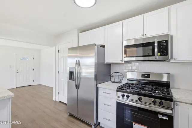 a kitchen with stainless steel appliances white cabinets and a stove top oven