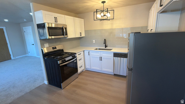 647 Swenson Avenue, Unit 4 Springville, UT 84663 - Photo 2 of 14 Kitchen featuring stainless steel appliances, white cabinetry, tasteful backsplash, and suspended lighting