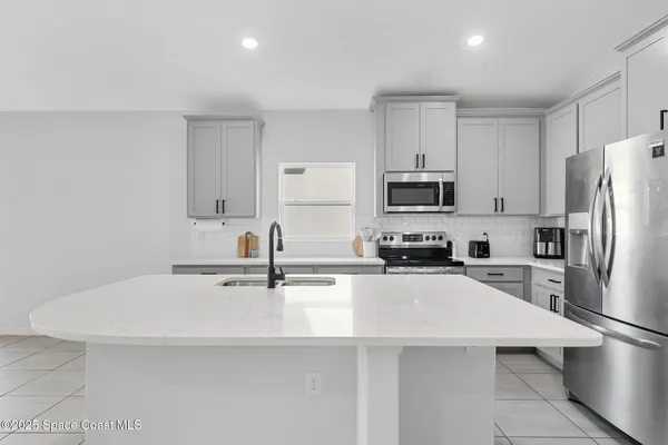 a kitchen with a sink dishwasher and white cabinets with wooden floor