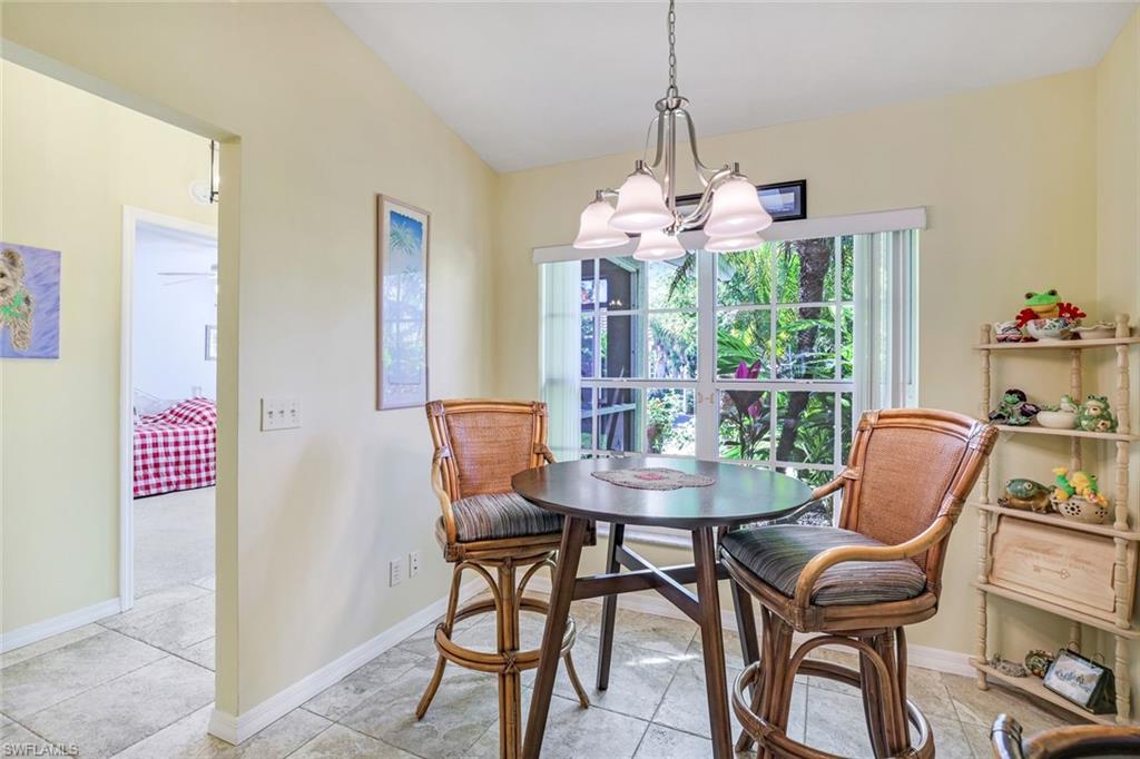 914 Augusta Boulevard, Unit 7 Naples, FL 34113 - Photo 9 of 32 Dining area with baseboards, vaulted ceiling, and a notable chandelier
