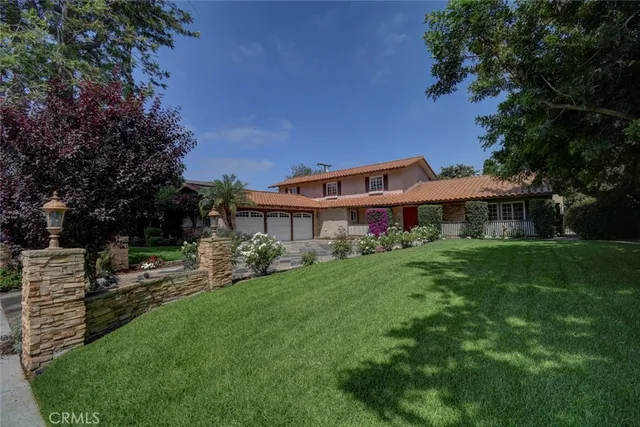 a front view of a house with a garden and trees