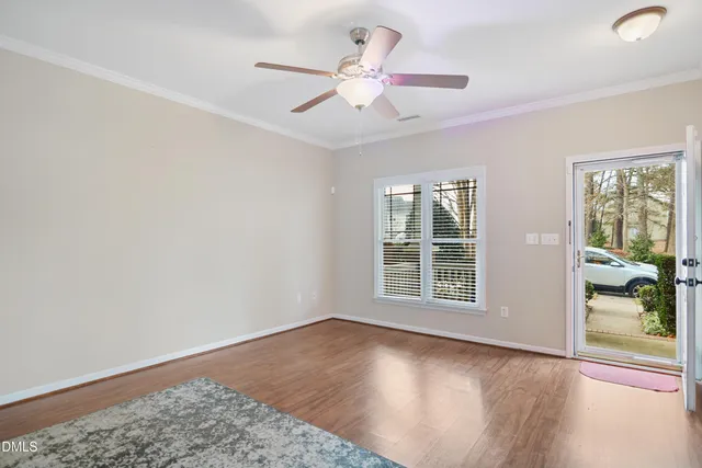 a view of an empty room with a window and wooden floor