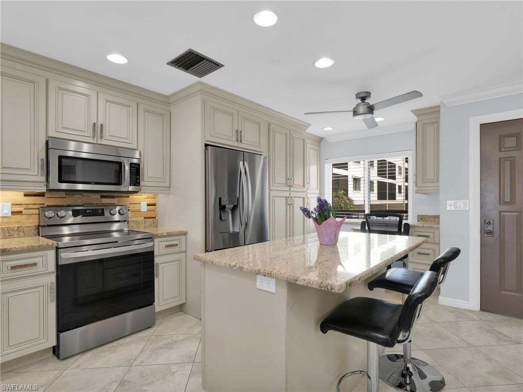 750 West Elkcam Circle, Unit 107 Marco Island, FL 34145 - Photo 5 of 33 Kitchen with cream cabinets, appliances with stainless steel finishes, light stone countertops, decorative backsplash, and recessed lighting