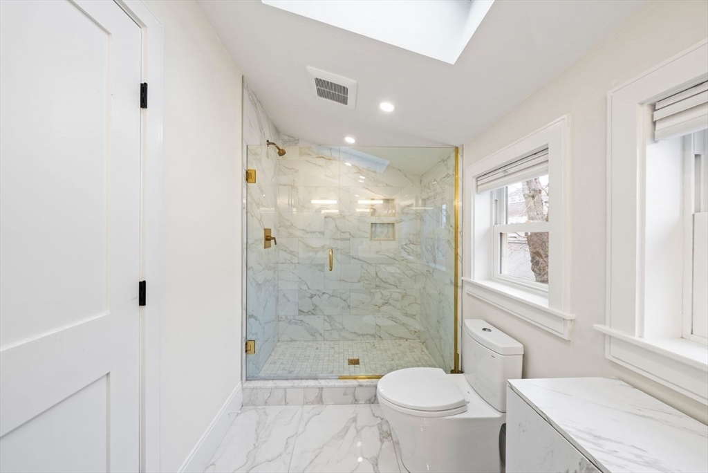 12-14 Porter Street, Unit 12 Boston, MA 02130 - Photo 28 of 37 a bathroom with a granite countertop toilet a sink and a shower