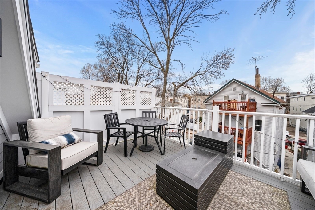 12-14 Porter Street, Unit 12 Boston, MA 02130 - Photo 32 of 37 a view of a roof deck with table and chairs with wooden floor and fence