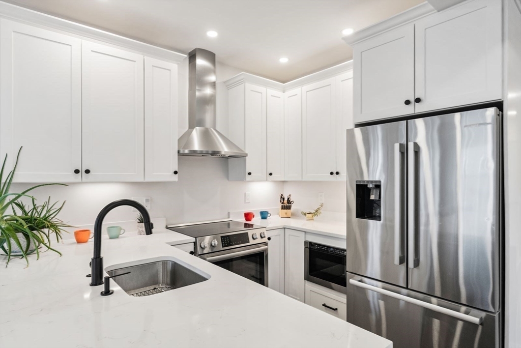 12-14 Porter Street, Unit 12 Boston, MA 02130 - Photo 9 of 37 a kitchen with stainless steel appliances granite countertop a refrigerator sink and white cabinets
