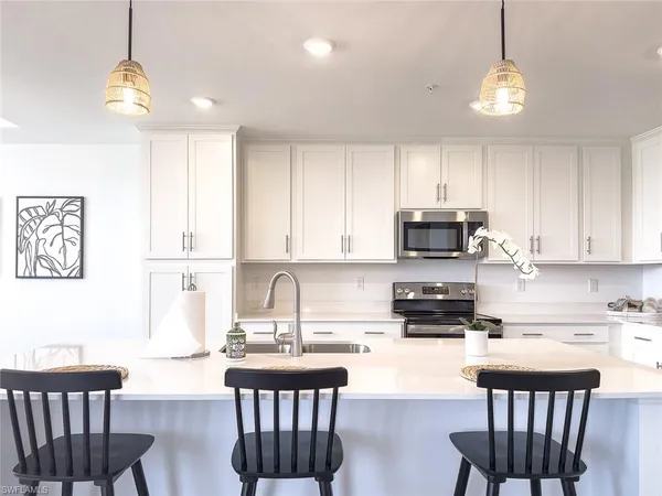 a kitchen with stainless steel appliances granite countertop a stove a sink dishwasher a microwave oven a stove with white cabinets and wooden floor