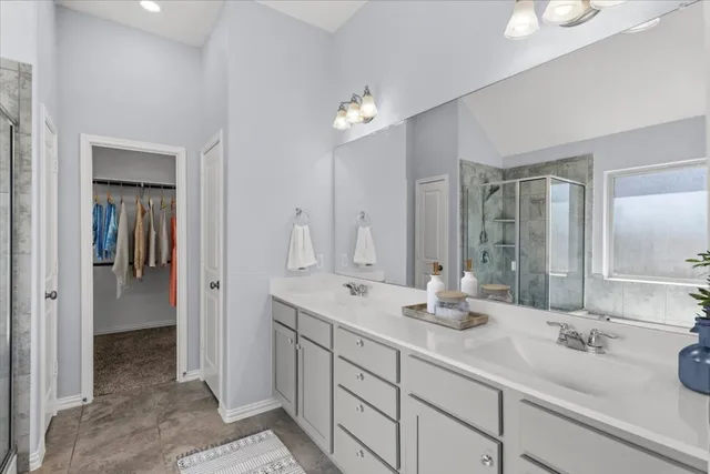 a bathroom with double vanity sinks a vanity a lamp and a mirror