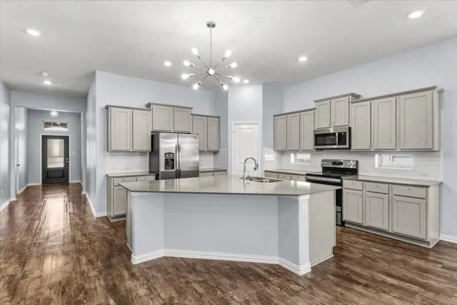 a kitchen with kitchen island granite countertop stainless steel appliances cabinets a sink and a counter top space