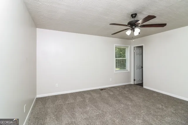 an empty room with a window and a fan