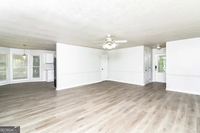 a view of an empty room with wooden floor and a window