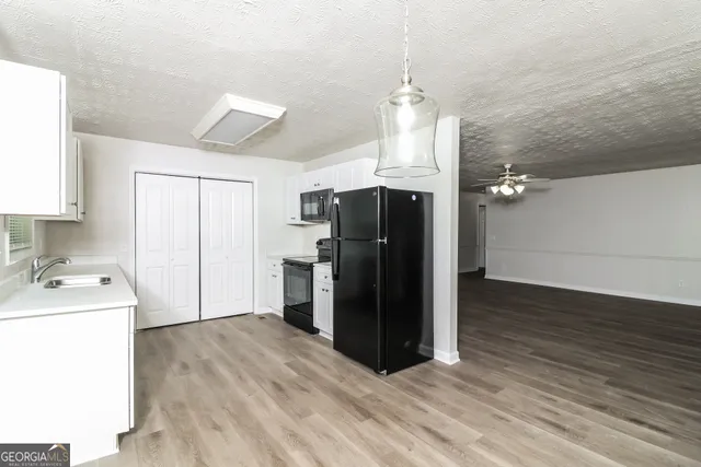 a view of a kitchen with refrigerator and wooden floor