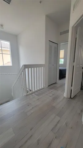 a view of a hallway with wooden floor and stairs