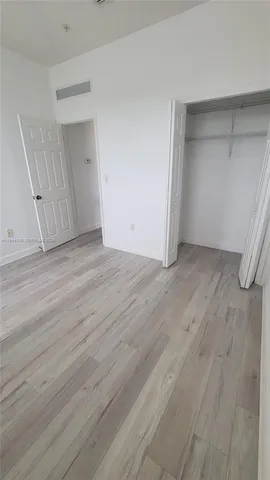 a view of an empty room with wooden floor and closet