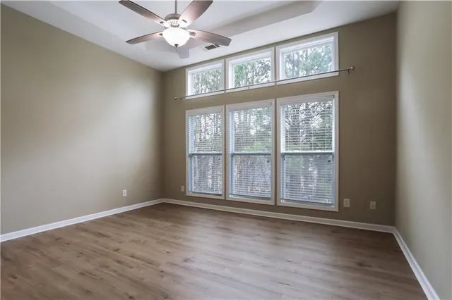 a view of an empty room with wooden floor and a window