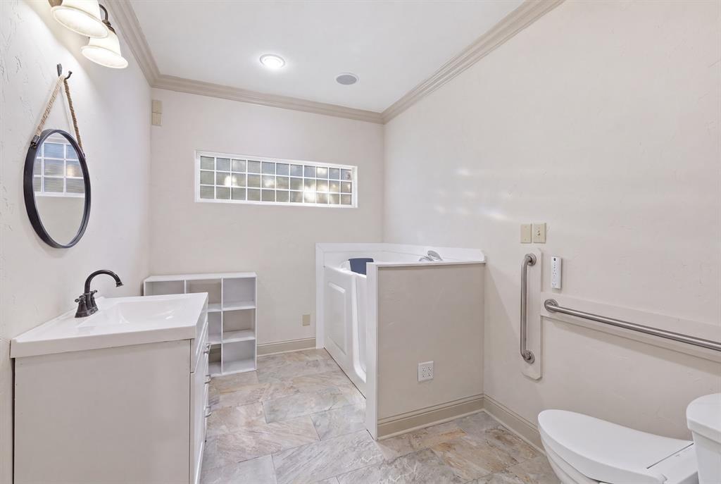 91 Private Road Pittsburg, TX 75686 - Photo 11 of 26 Bathroom featuring a vanity with an integrated sink, a walk-in tub, and a toilet