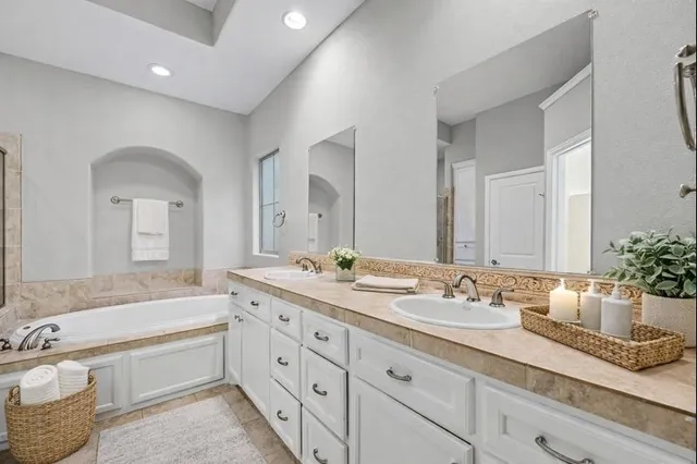 a spacious bathroom with a granite countertop double vanity sink a mirror and a bathtub