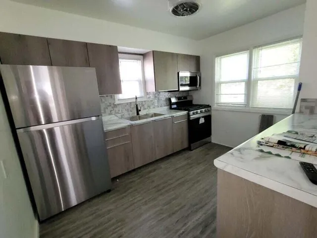 a kitchen with stainless steel appliances granite countertop a refrigerator a sink a stove a microwave a refrigerator a sink and dishwasher with wooden floor