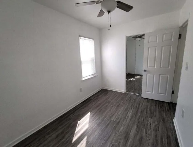 an empty room with wooden floor cabinet and windows