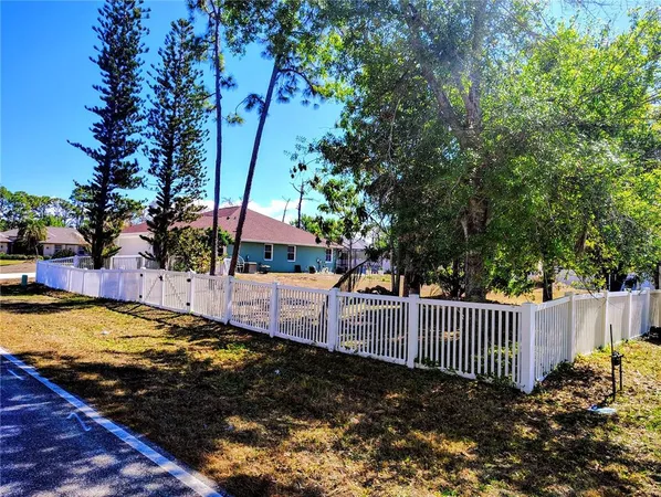 a view of a backyard with fence and a tree