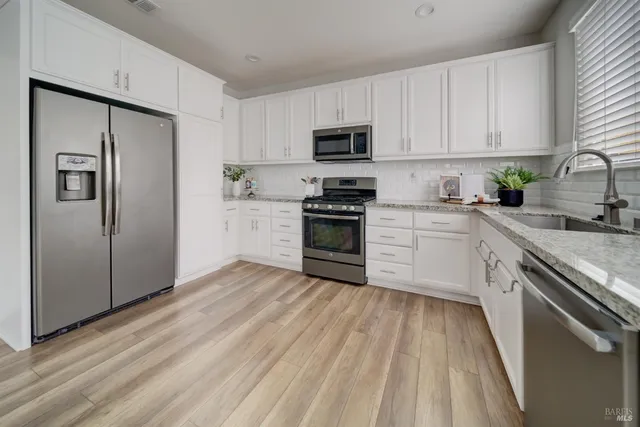a kitchen with white cabinets stainless steel appliances and a window