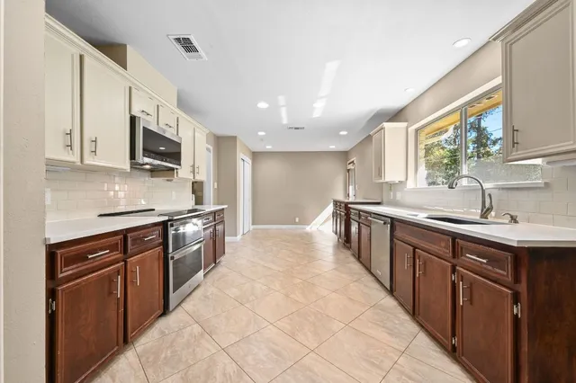 a large kitchen with stainless steel appliances granite countertop a sink stove and refrigerator