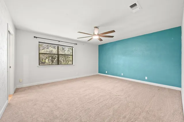 an empty room with windows and fan