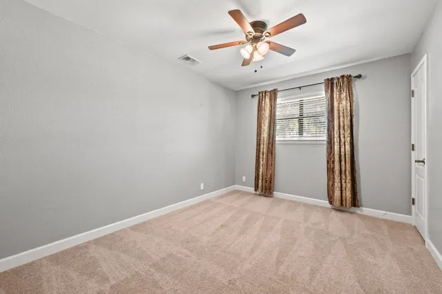 an empty room with chandelier fan and windows