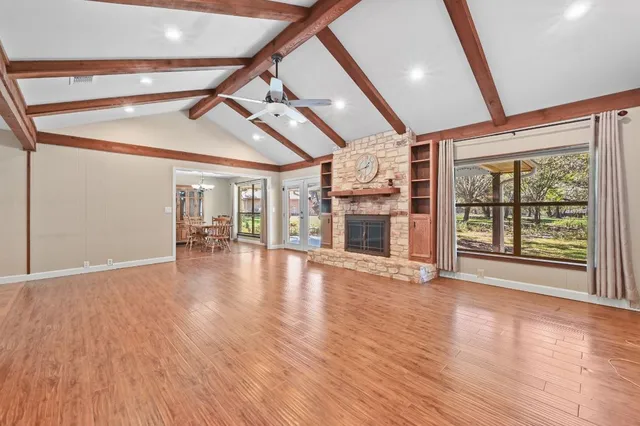 a view of an empty room with wooden floor fireplace and a window