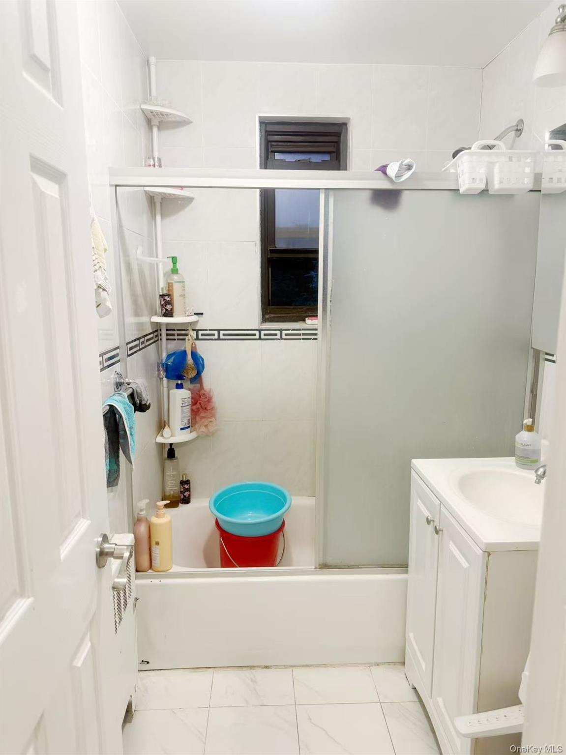 46 Terrace Circle, Unit 2C Great Neck, NY 11021 - Photo 9 of 14 Full bath featuring combined bath / shower with glass door, vanity, and marble look tiles