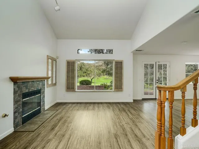 a view of an empty room with wooden floor and stairs