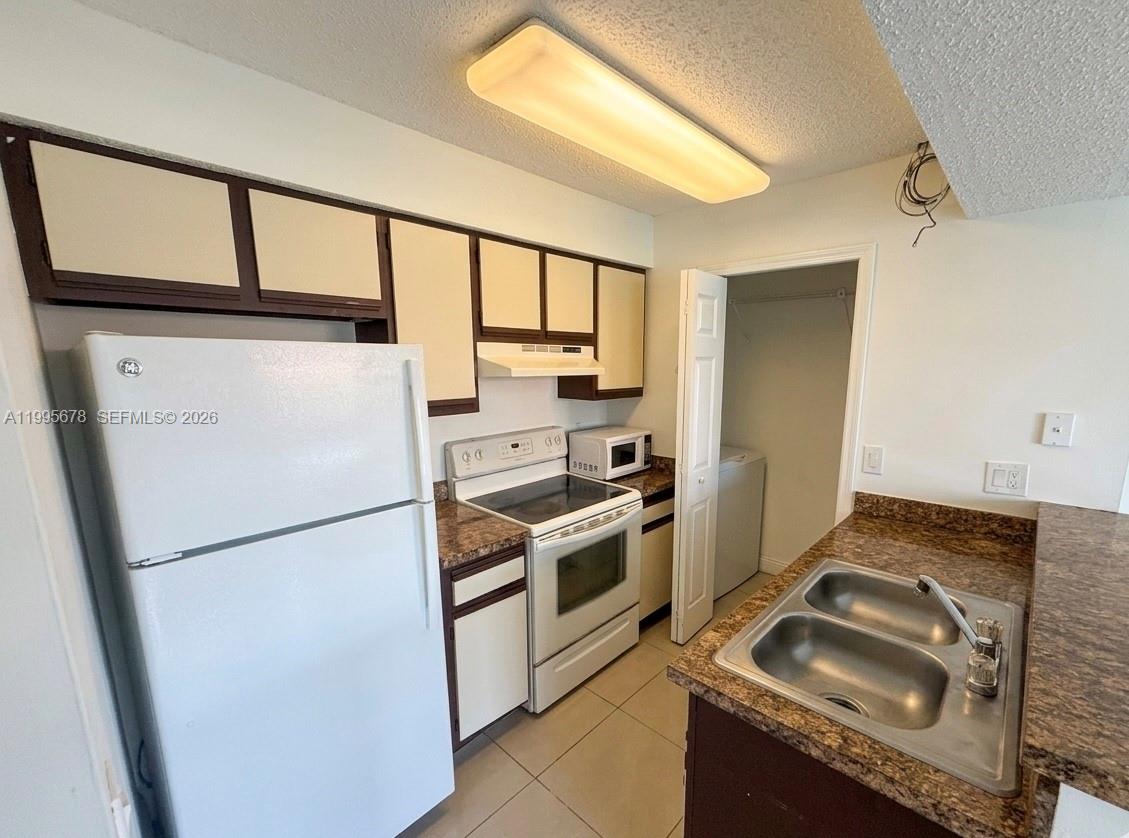 1253 Southwest 46th Avenue, Unit 1608 Pompano Beach, FL 33069 - Photo 5 of 14 a kitchen with a stove a refrigerator and a sink
