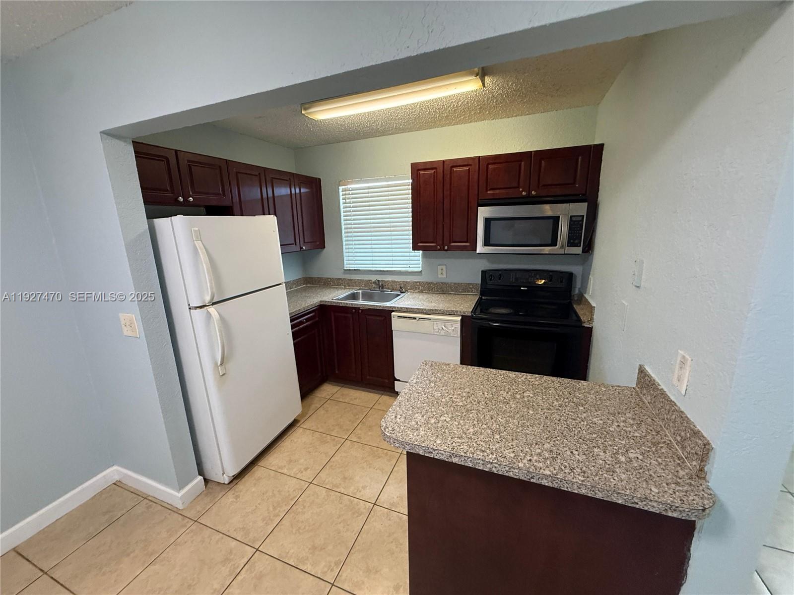 400 Northwest 65th Avenue, Unit 227 Margate, FL 33063 - Photo 9 of 13 a kitchen with a refrigerator and a stove top oven