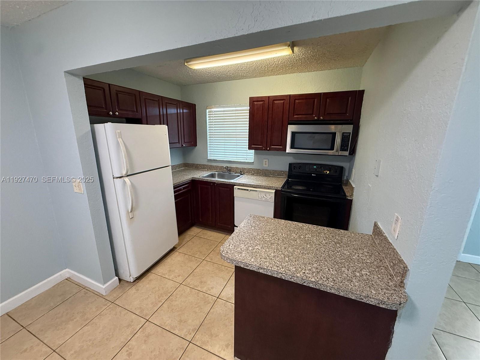 400 Northwest 65th Avenue, Unit 227 Margate, FL 33063 - Photo 10 of 13 a kitchen with a sink a refrigerator and a stove top oven