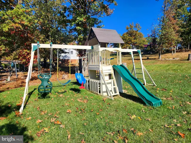 a view of playground with a slide and large trees