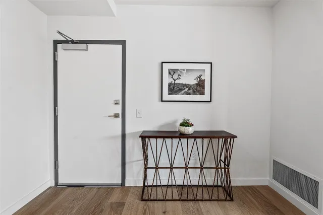 a view of a hallway with wooden floor and a bathroom