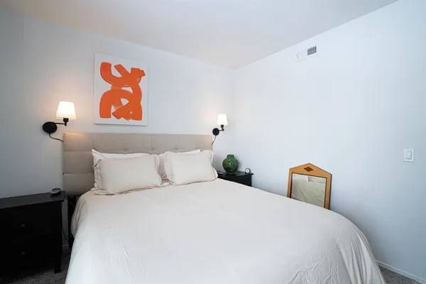 a bedroom with a bed and a painting on the wall