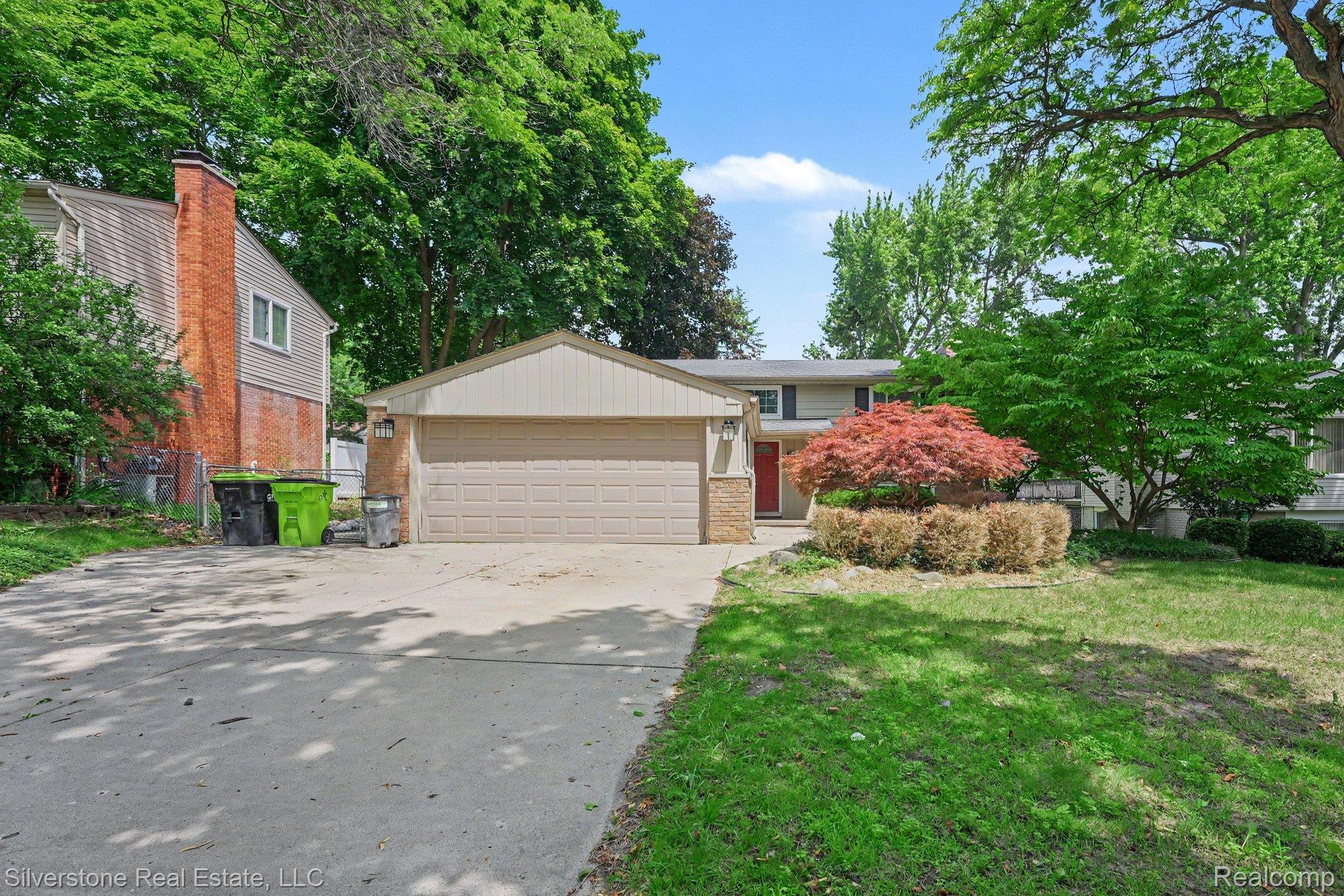 547 Reed Street Northville, MI 48167 - Photo 2 of 38 Split-level residence featuring a two-car garage, concrete driveway, and established front yard landscaping with mature trees