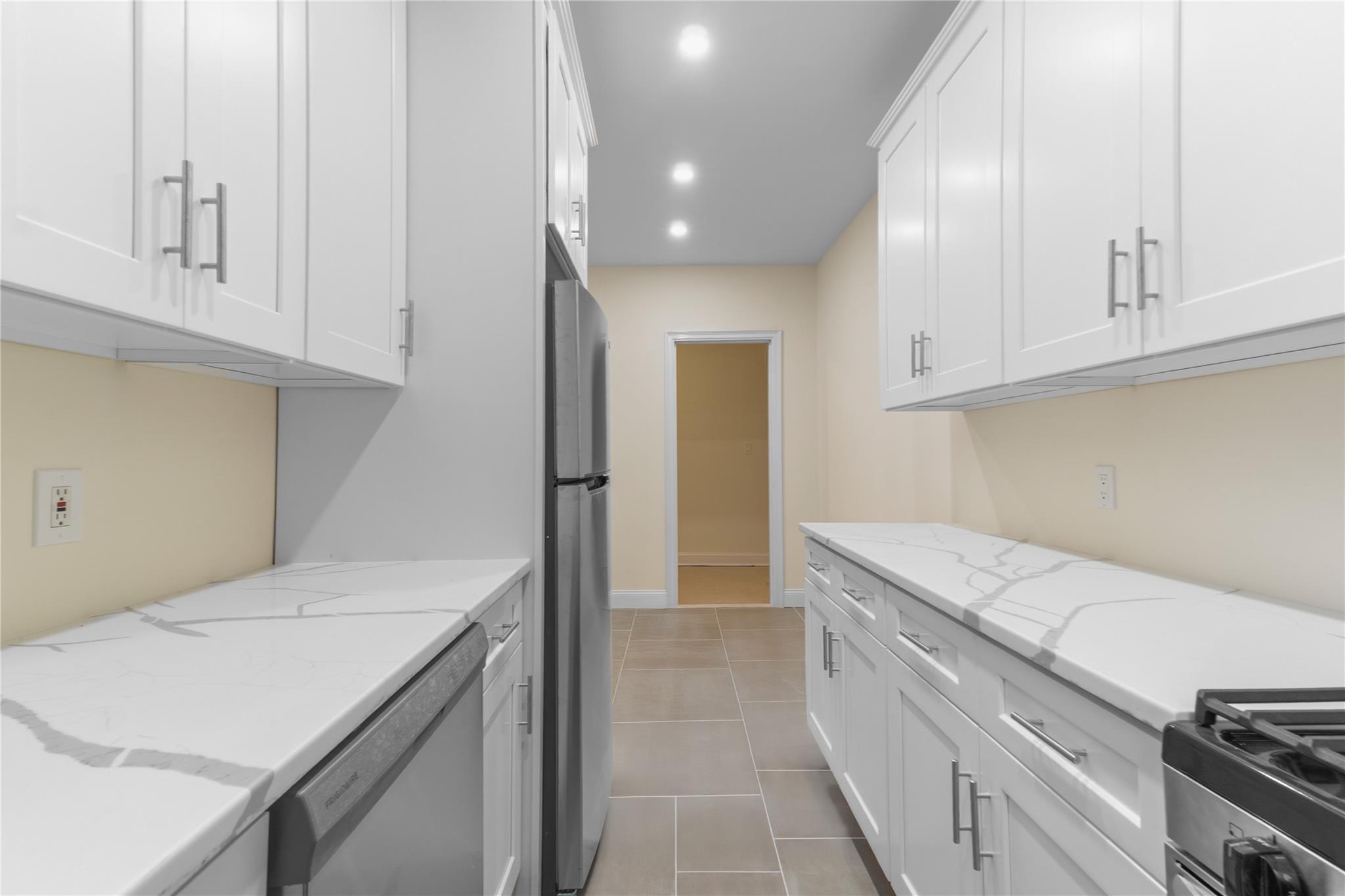 110-07 73rd Road, Unit 4D Queens, NY 11375 - Photo 11 of 16 Kitchen featuring appliances with stainless steel finishes, white cabinetry, light tile patterned floors, recessed lighting, and light stone countertops