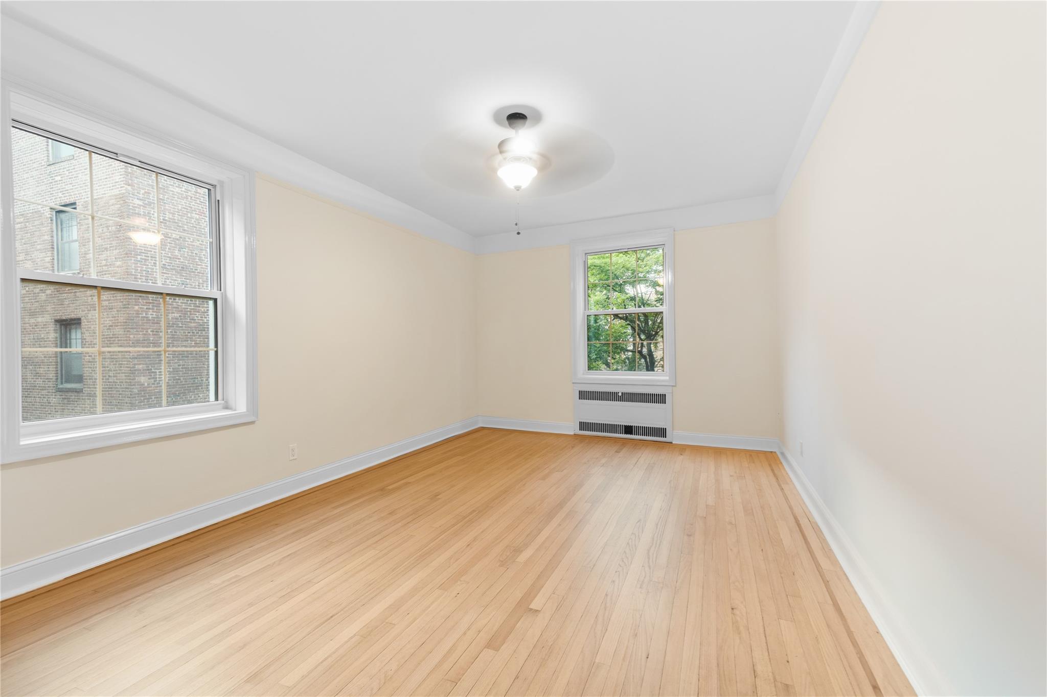 110-07 73rd Road, Unit 4D Queens, NY 11375 - Photo 5 of 16 Spare room featuring light wood-type flooring, baseboards, and ceiling fan