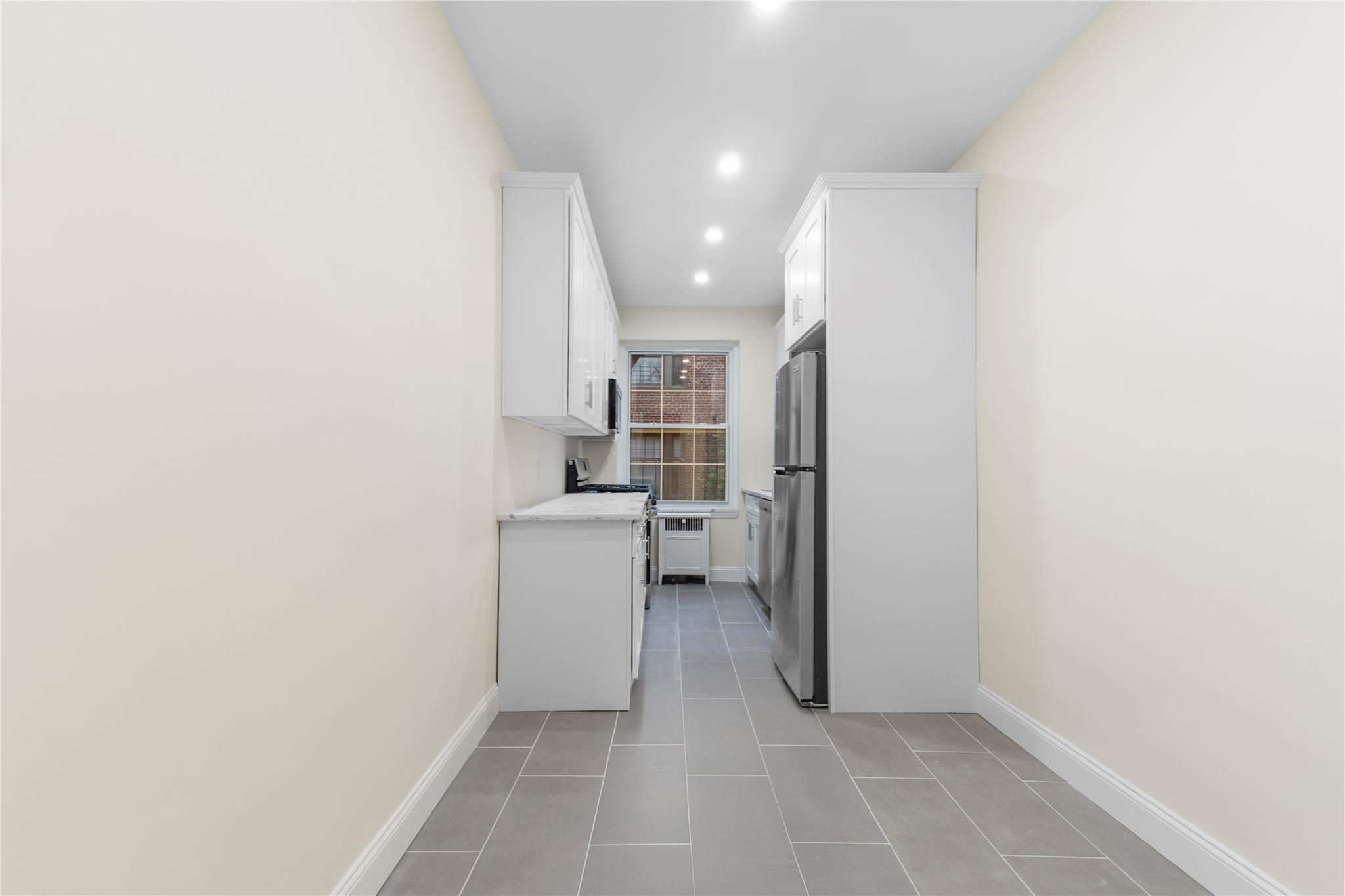 110-07 73rd Road, Unit 4D Queens, NY 11375 - Photo 9 of 16 Kitchen with appliances with stainless steel finishes, white cabinetry, recessed lighting, light countertops, and baseboards