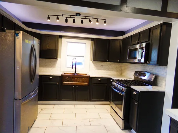 a kitchen with stainless steel appliances granite countertop a refrigerator a sink a stove top oven and a dishwasher