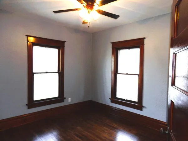 a view of an empty room with wooden floor and a window