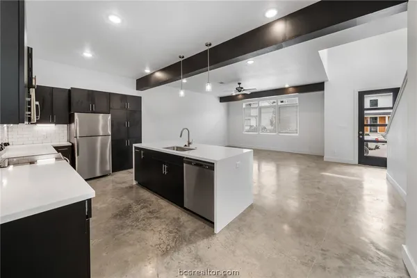 a large kitchen with stainless steel appliances a sink and a refrigerator