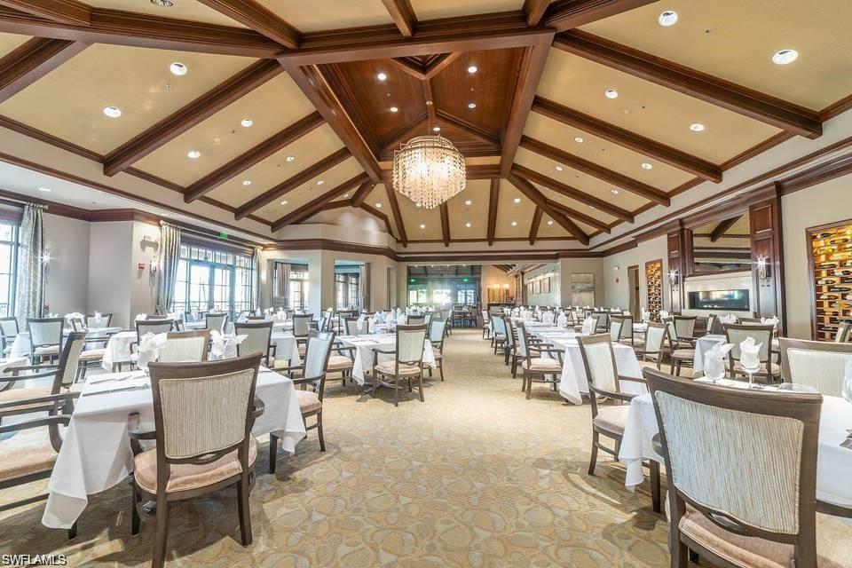 7587 Moorgate Point Way Naples, FL 34113 - Photo 48 of 50 Elegant banquet hall featuring coffered wood-beam ceiling with integrated recessed lighting, crystal chandelier, and large windows providing natural illumination